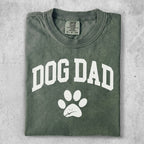 Green t-shirt with white "DOG DAD" text and paw print.