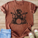 Dachshund playing drums graphic on a distressed rust colored t-shirt.