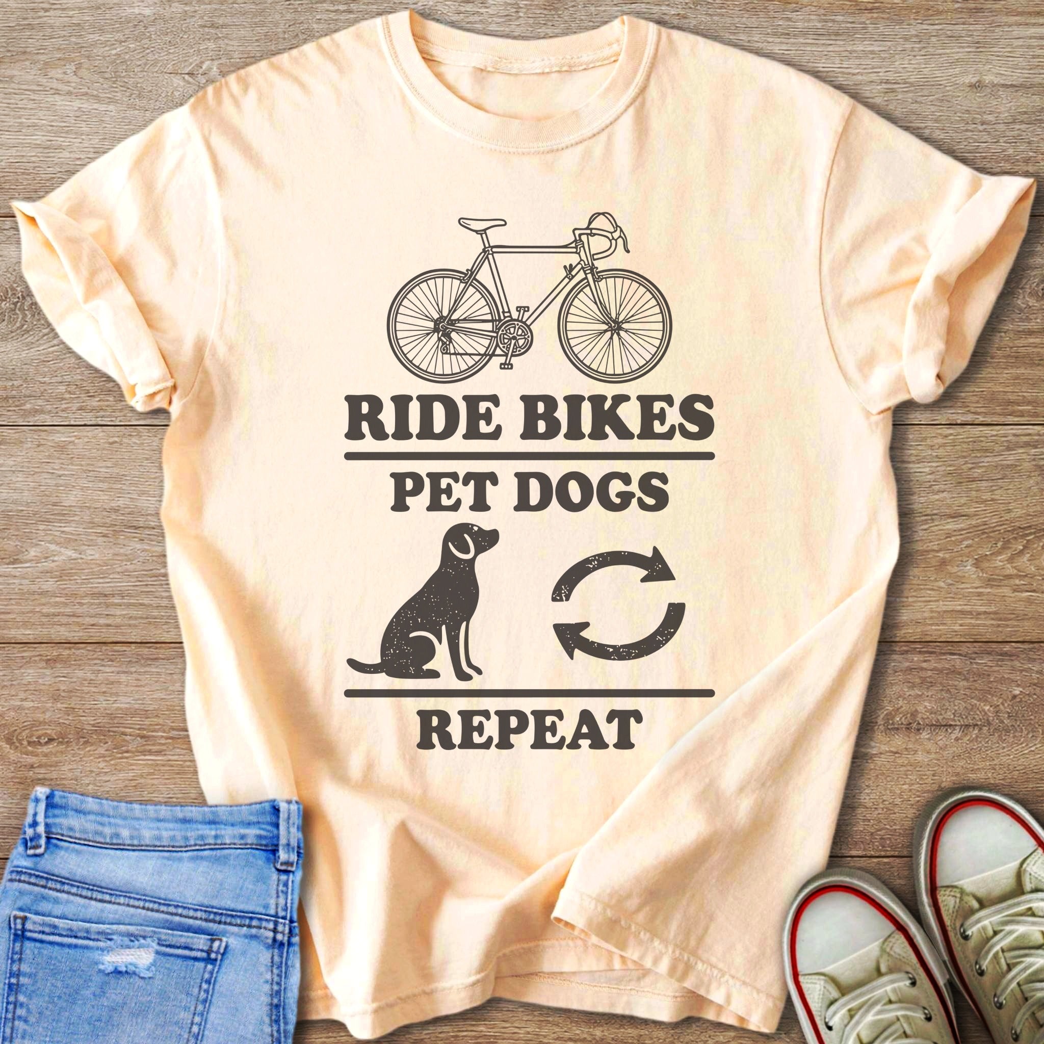 Peach t-shirt with "Ride Bikes Pet Dogs Repeat" graphic and biking symbols.