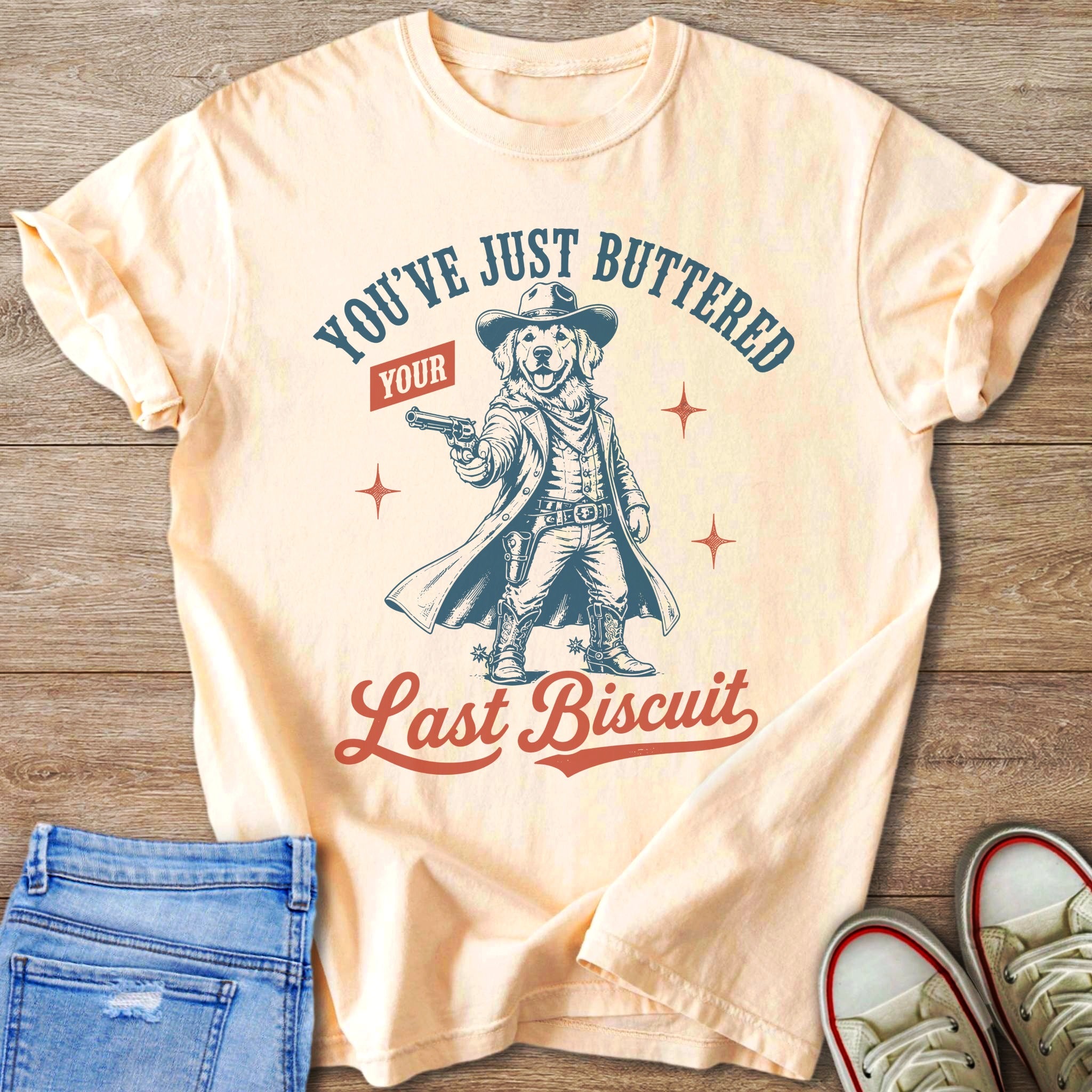 T-shirt graphic of a golden retriever dressed as a cowboy holding a gun.