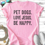 Pink t-shirt with black text "PET DOGS. LOVE JESUS. BE HAPPY."