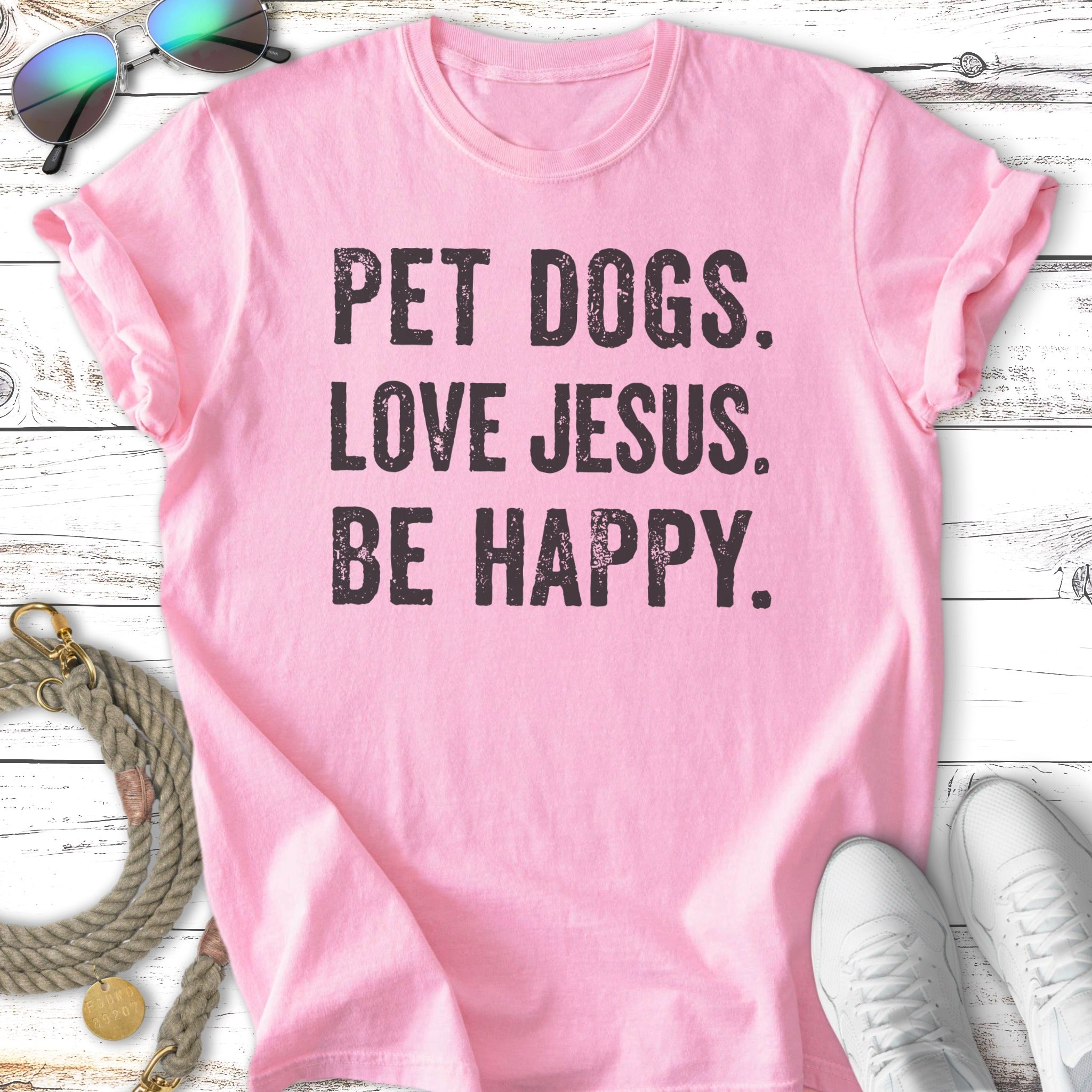 Pink t-shirt with black text "PET DOGS. LOVE JESUS. BE HAPPY."