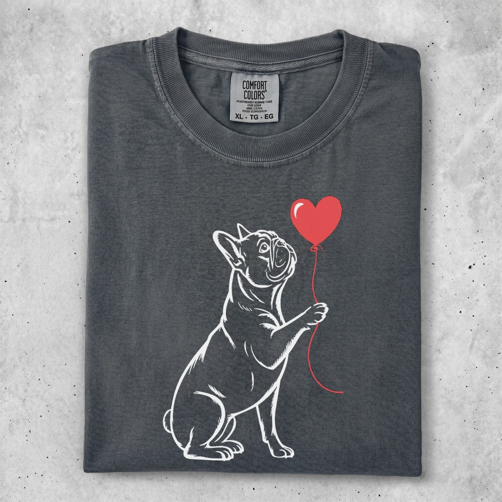 French bulldog holding a red heart balloon.