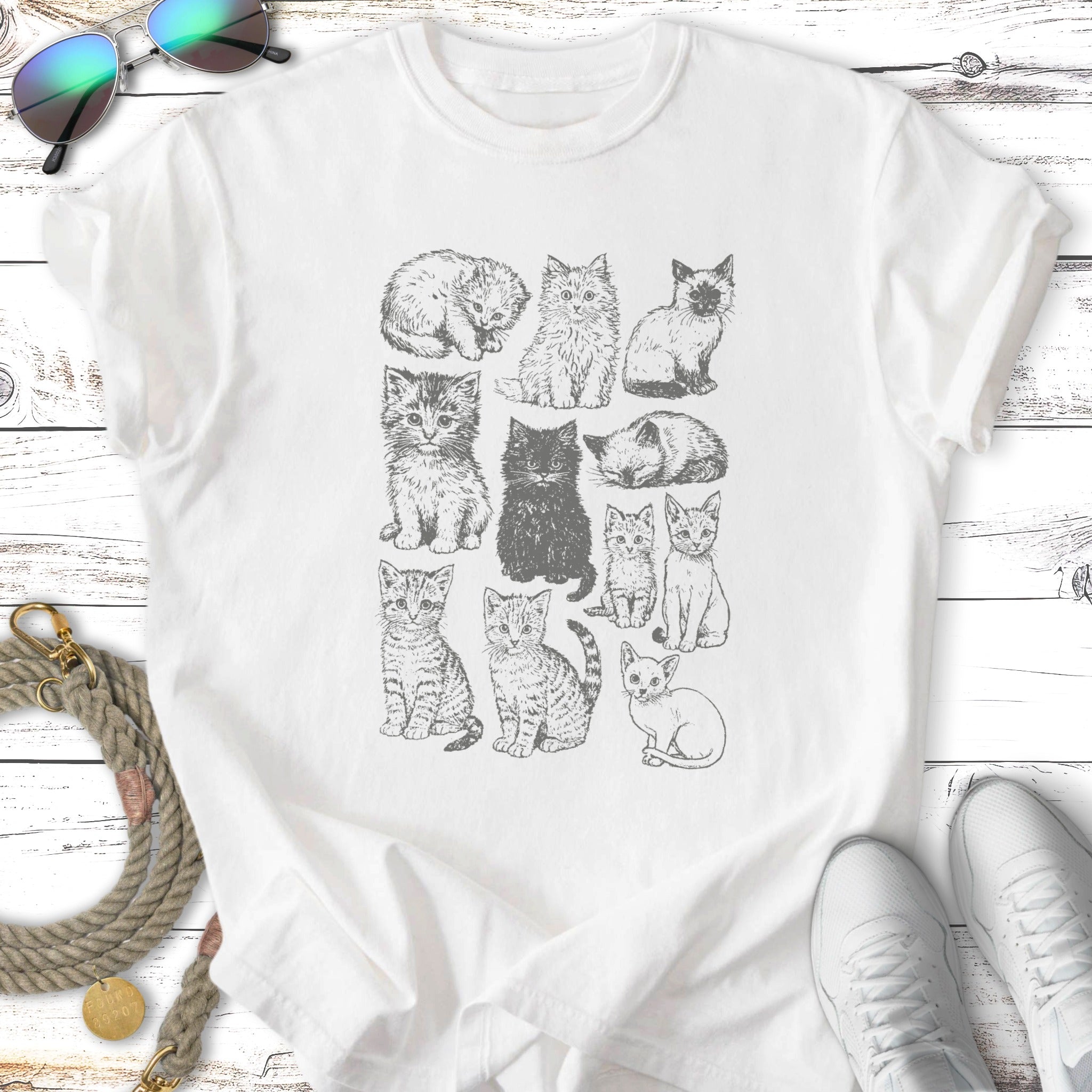 Sketch of twelve cats in various poses on a white t-shirt.