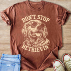 Brown t-shirt with "Don't Stop Retrieving" text and sunglasses-wearing dog graphic.