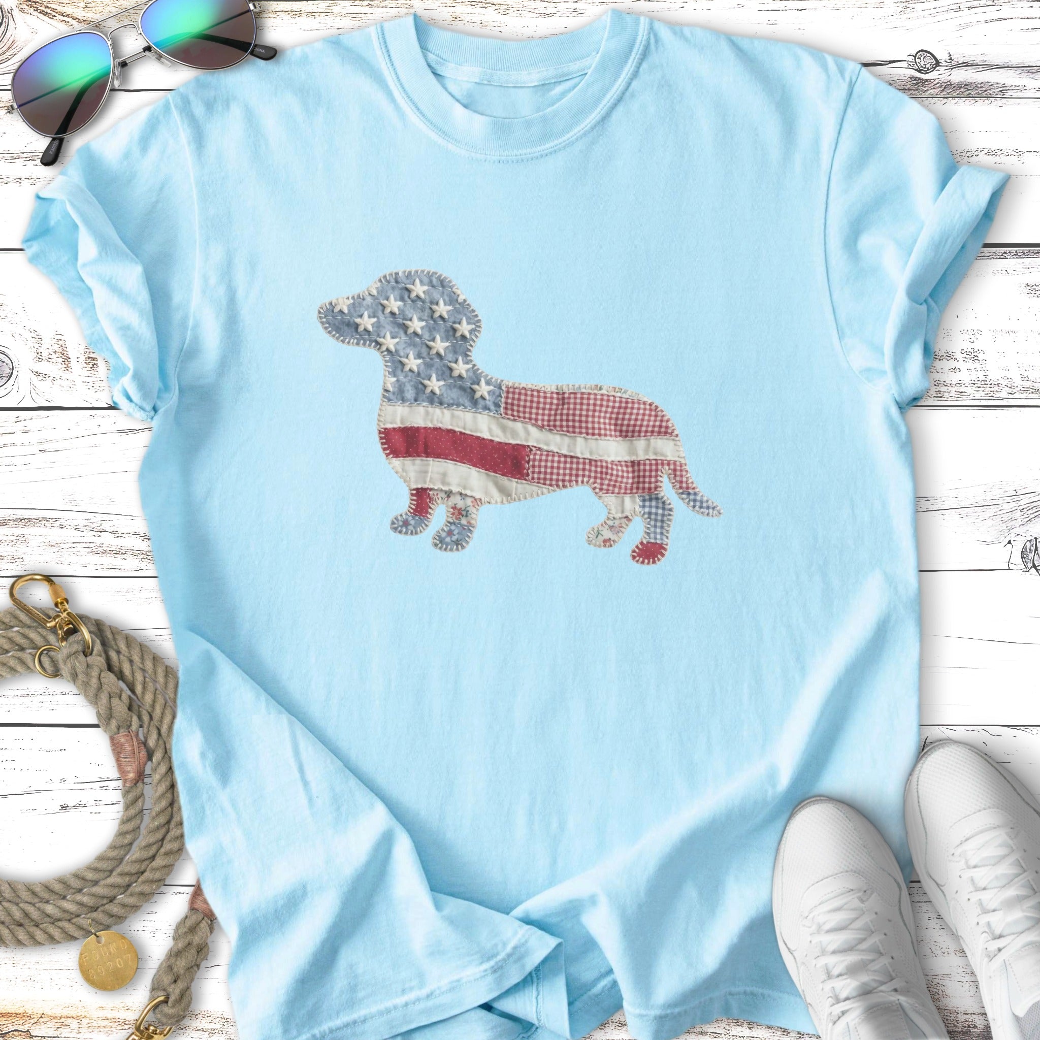 Light blue t-shirt with a patchwork dachshund made of American flag and plaid fabric.