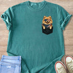 Teal t-shirt with a Pomeranian peeking from a black pocket, wearing American flag sunglasses and bandana.