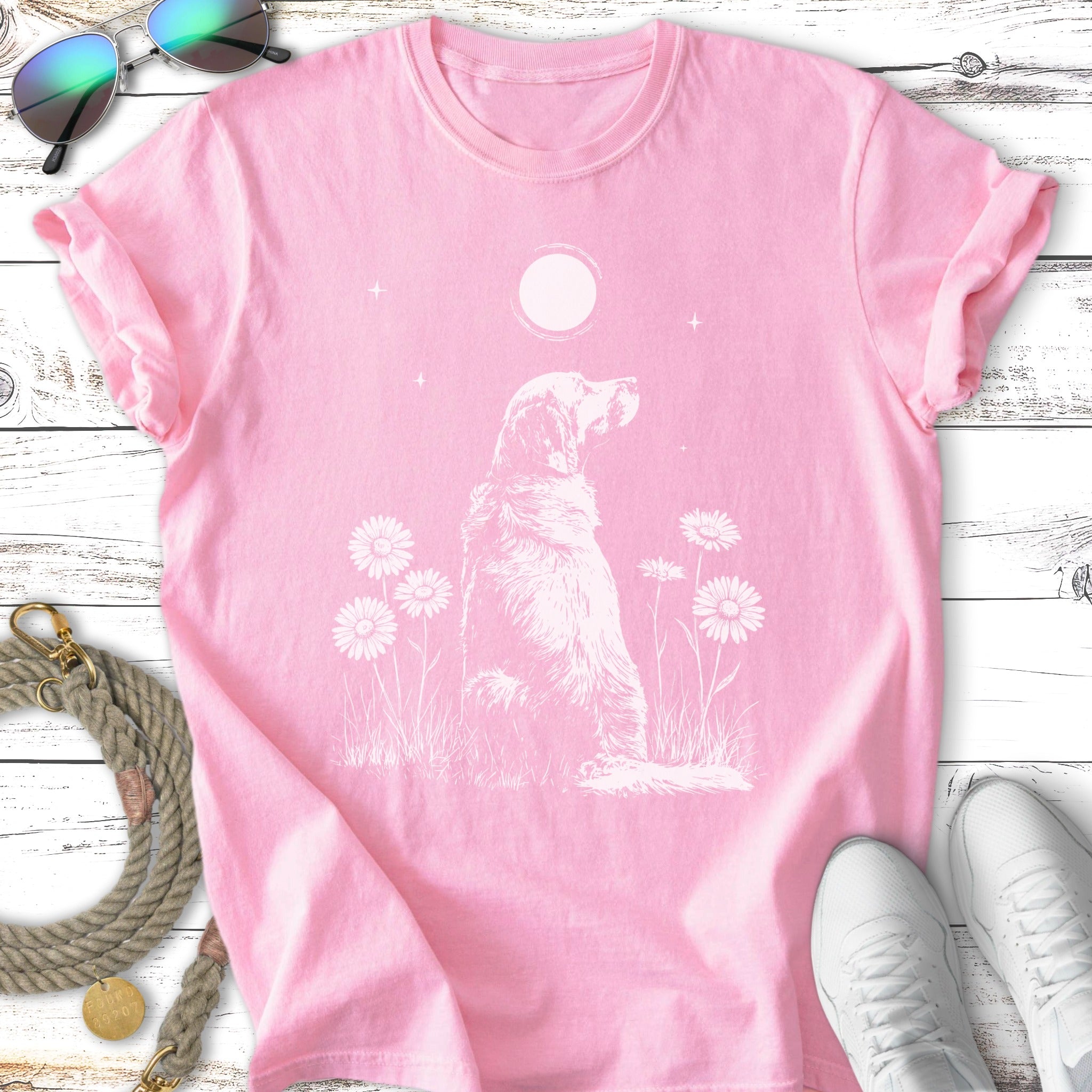 Pink t-shirt with a white line drawing of a dog sitting among daisies.