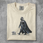 Darth Vader walking a small AT-AT on a leash, on a cream t-shirt.