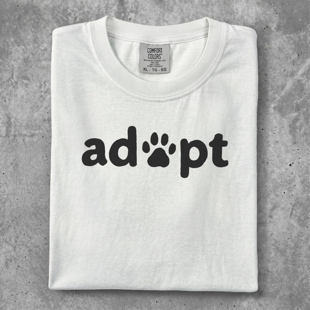 White t-shirt with black "adopt" text and paw print logo.