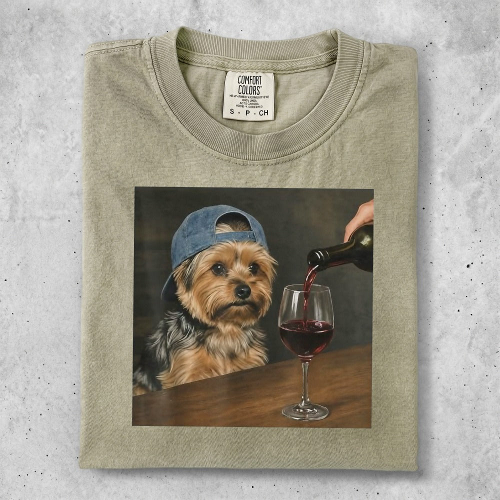 Dog wearing a blue baseball cap drinks red wine from a glass.