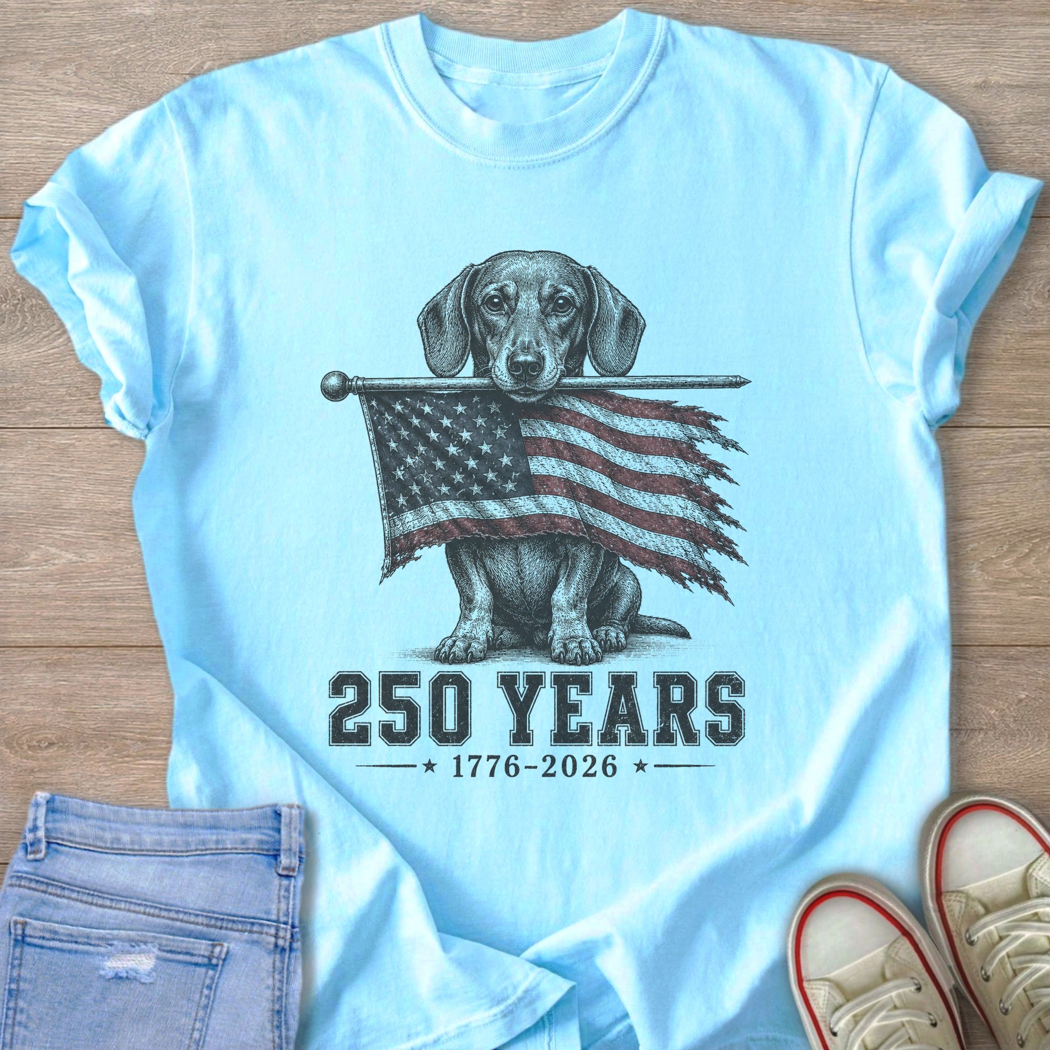 Light blue t-shirt with a dachshund holding an American flag and text "250 YEARS 1776-2026"