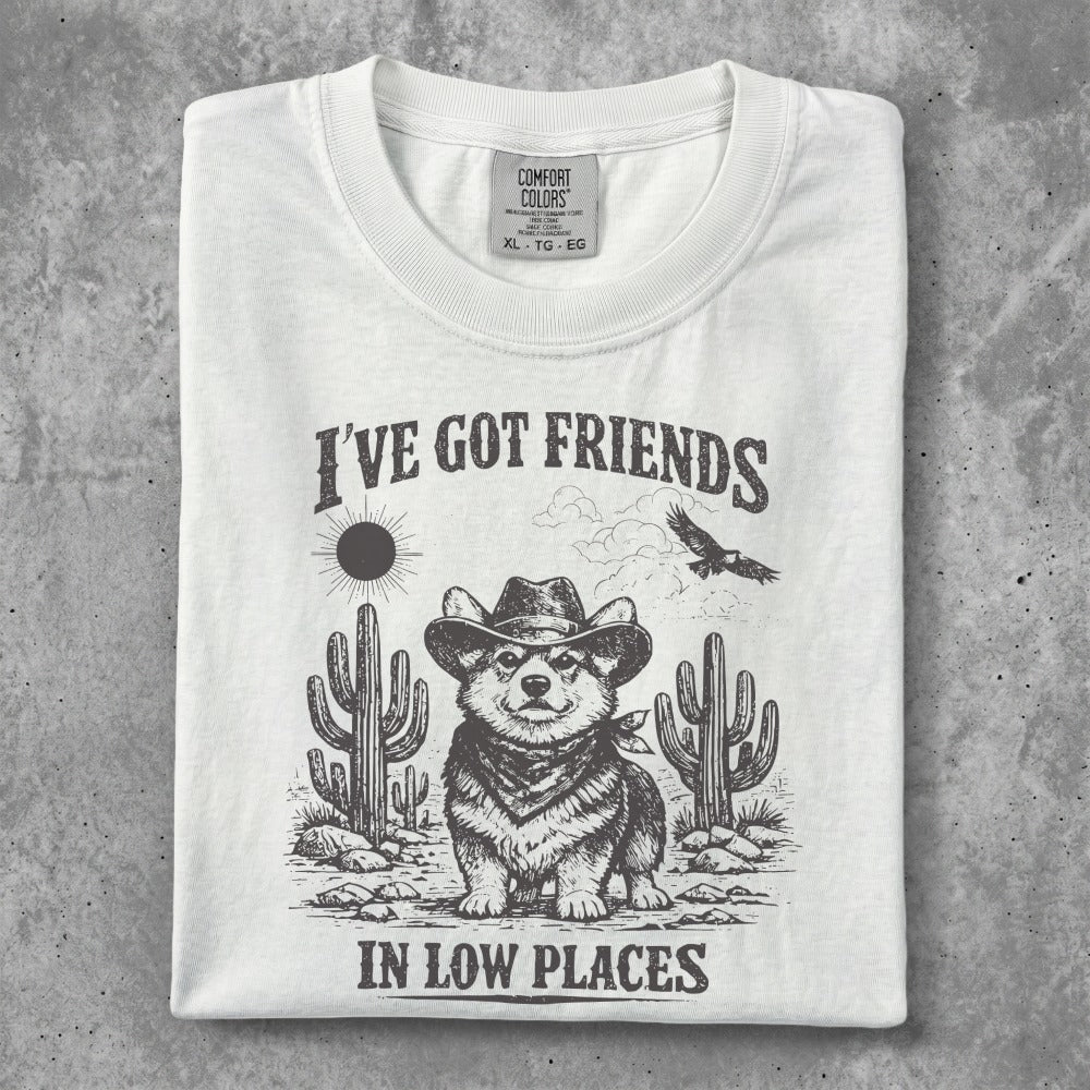 White t-shirt with corgi in cowboy hat, cacti, and text: I've got friends in low places.