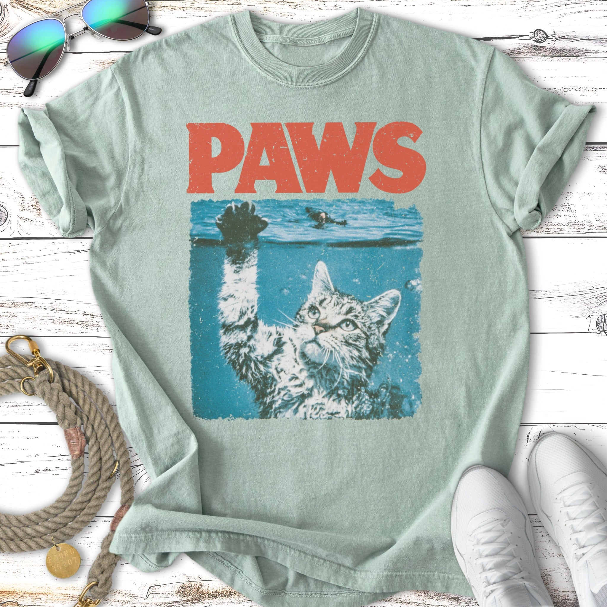 Cat in water reaching up, with "PAWS" text above.