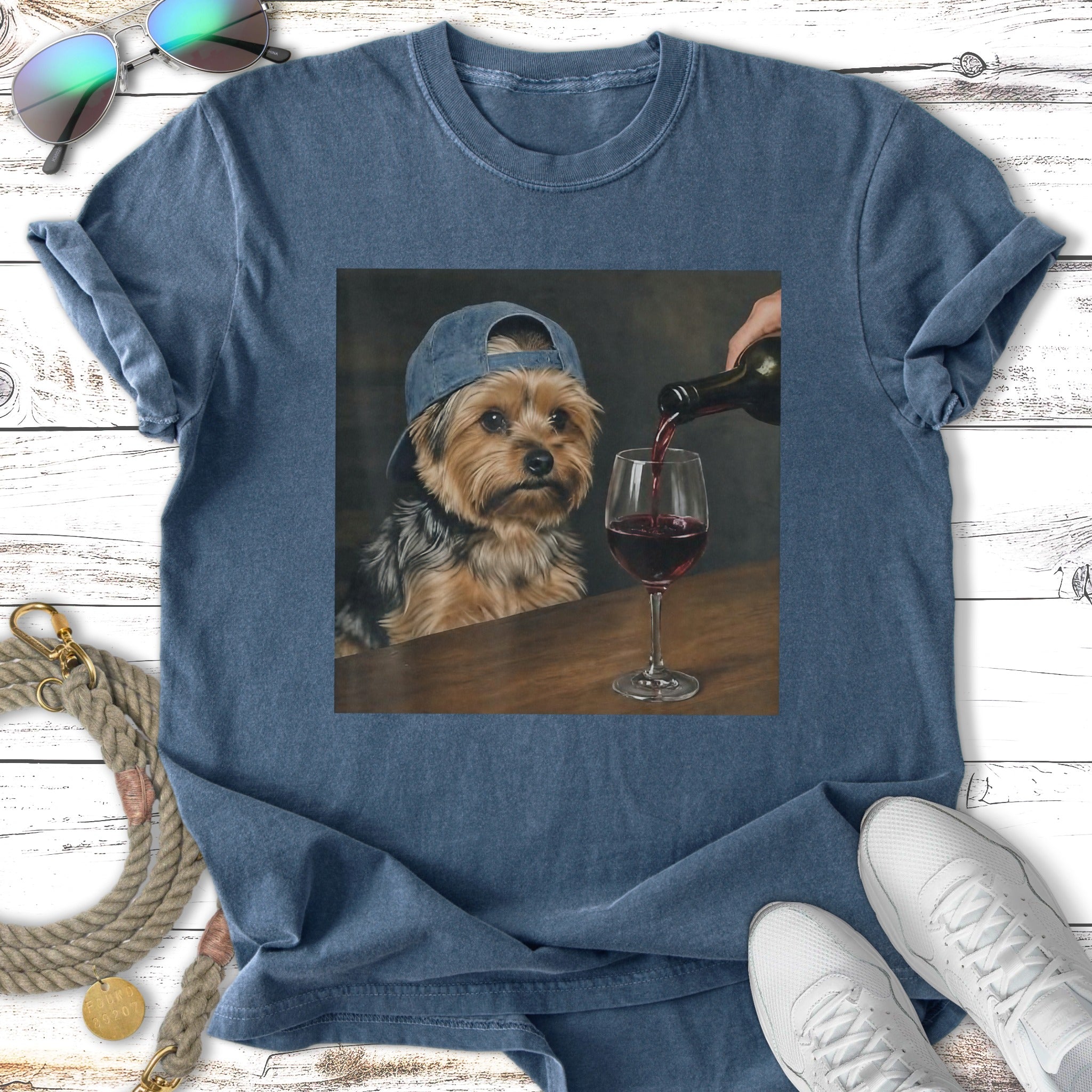 Yorkshire terrier in baseball cap sips red wine from a glass.