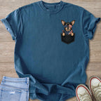 Chihuahua wearing sunglasses peeking out of a t-shirt pocket.