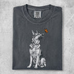 German Shepherd dog looking up at a monarch butterfly on dark grey t-shirt.
