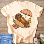 Dachshund in sunglasses and hot dog bun lying under umbrella, with sunscreen and flip-flops.