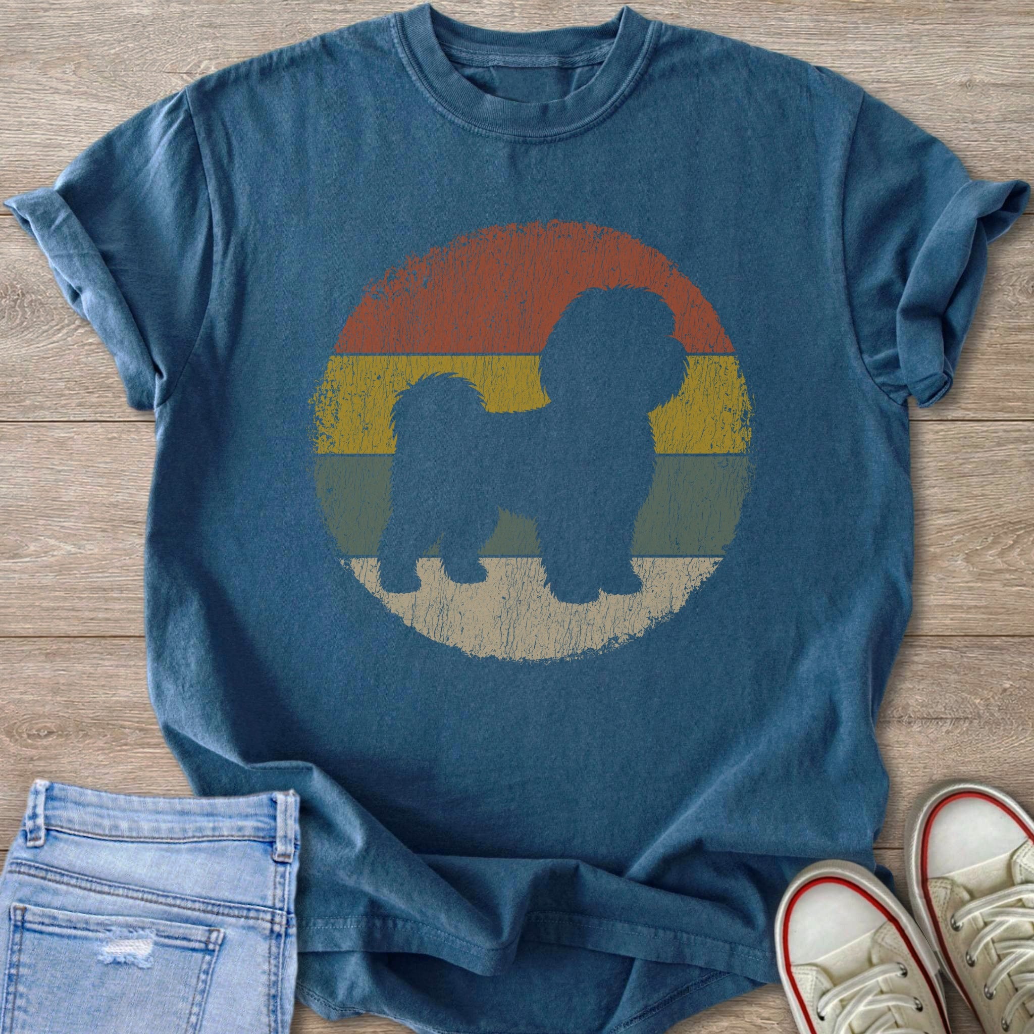 Blue t-shirt with a silhouette of a fluffy dog inside a retro striped circle.