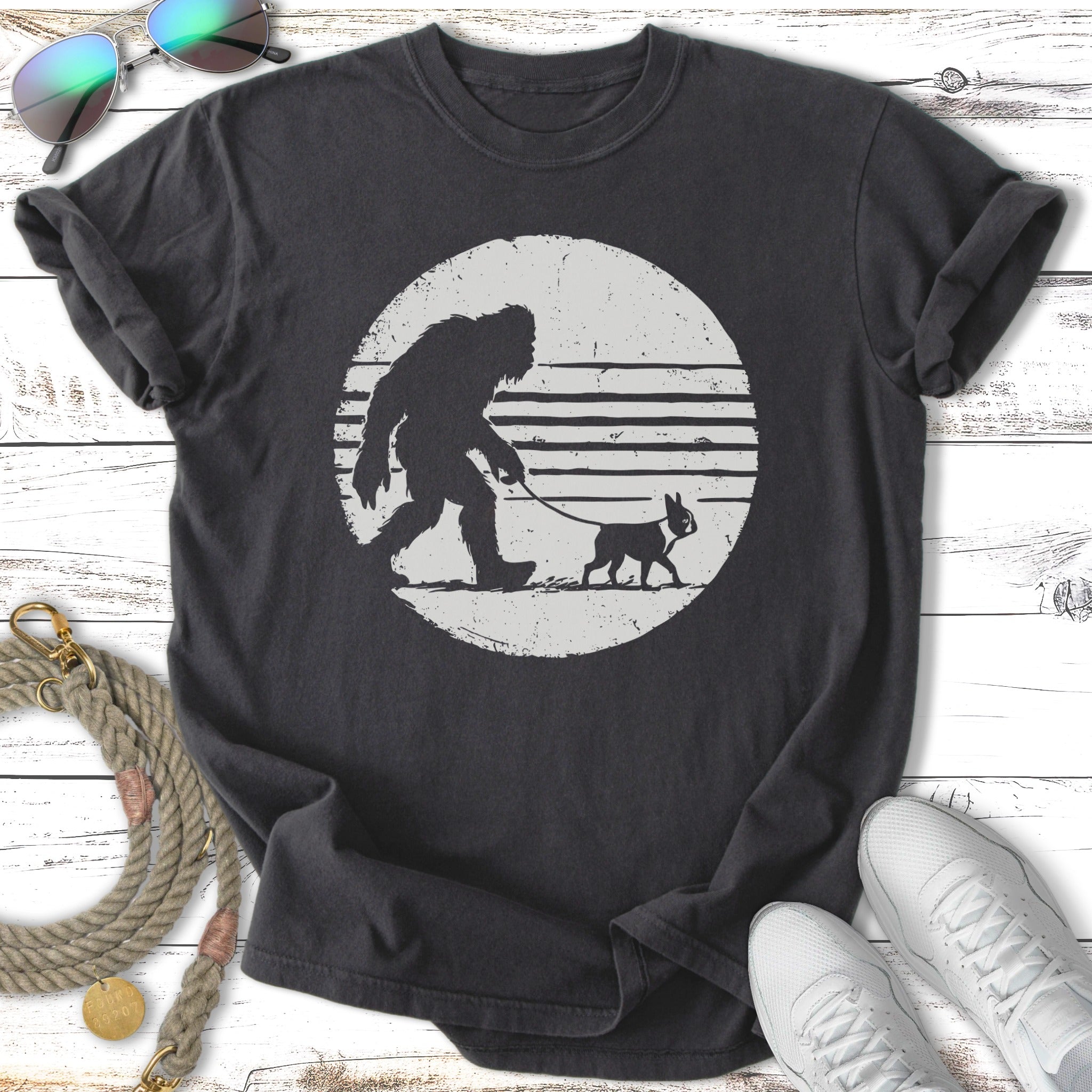 Bigfoot walking a small dog on a leash, silhouetted against a circular graphic.