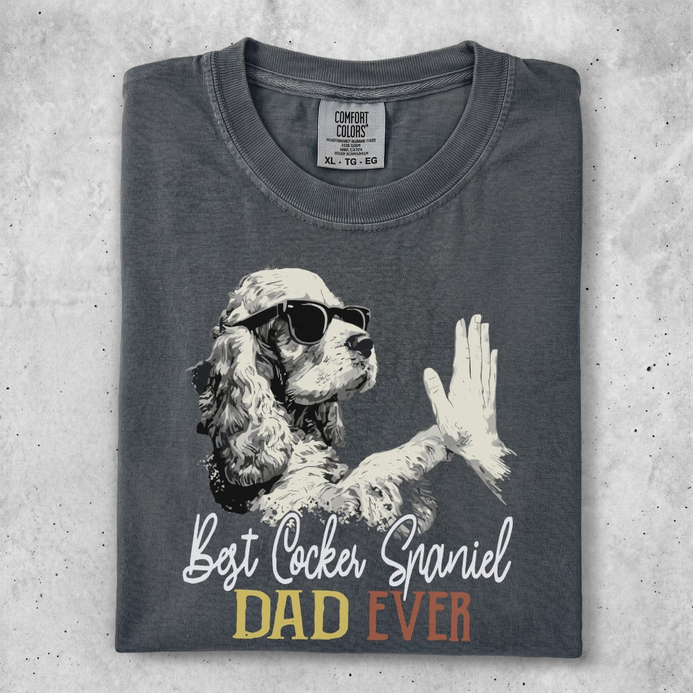 Cocker Spaniel wearing sunglasses gives a high-five on a charcoal t-shirt.