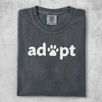 Dark gray t-shirt with "adopt" and a paw print graphic.