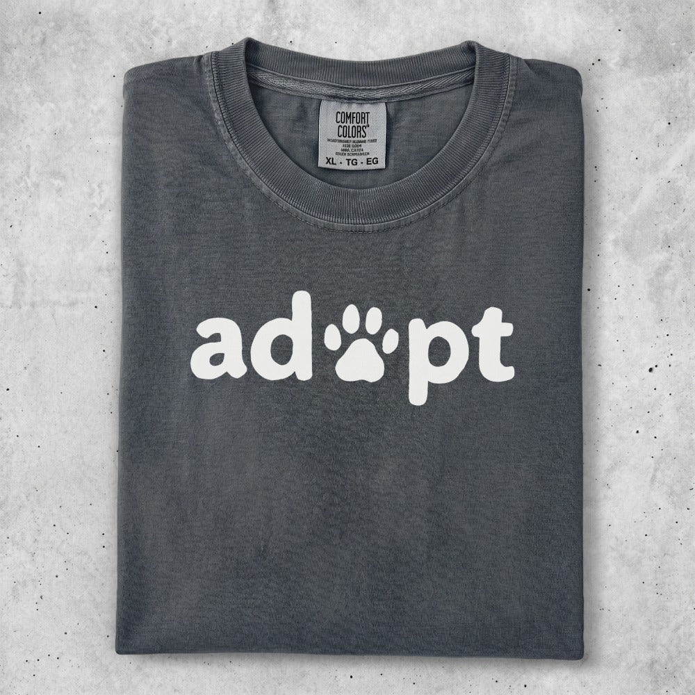 Dark gray t-shirt with "adopt" and a paw print graphic.