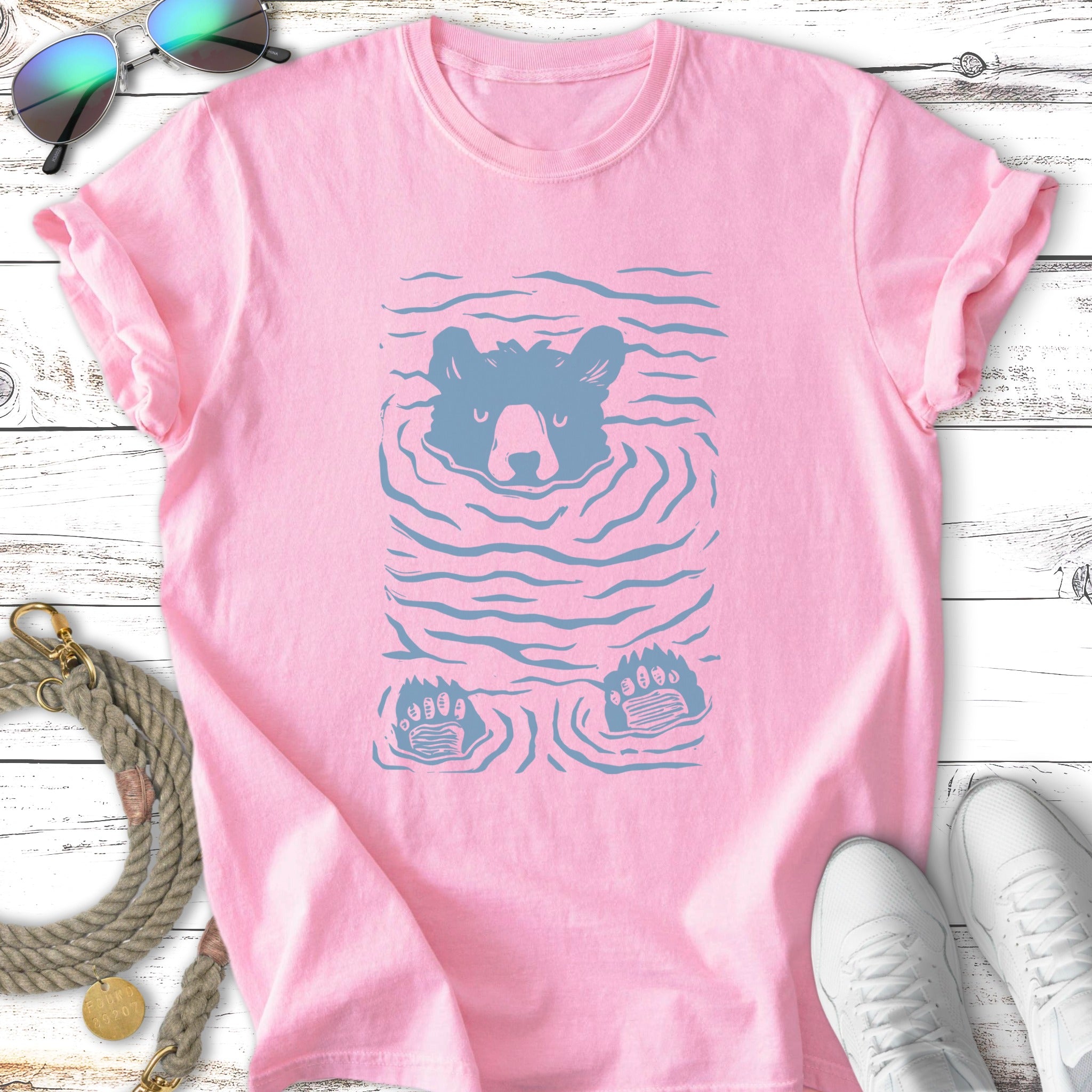Pink t-shirt with a stylized blue bear head and paws emerging from water.