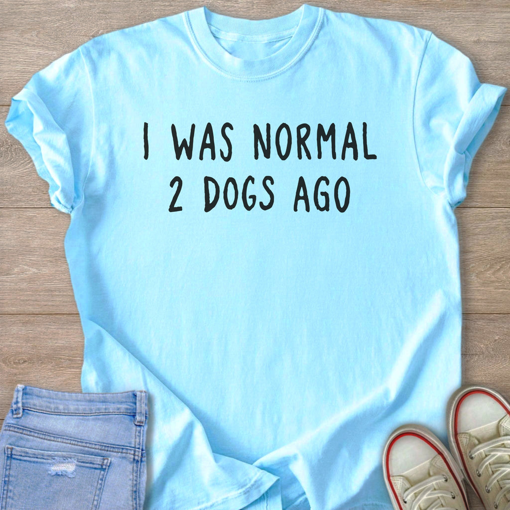 Light blue t-shirt with black text that reads "I WAS NORMAL 2 DOGS AGO".