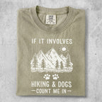 Graphic tee with mountains, trees, paw prints, and text "IF IT INVOLVES HIKING & DOGS - COUNT ME IN".