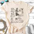 Sketch of nine cats in rows on a cream t-shirt.