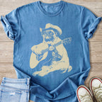 Blue t-shirt with a cream-colored pug wearing a cowboy hat and playing guitar graphic.