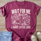 Maroon t-shirt with a graphic of a dachshund in mountains, saying "WAIT FOR ME I HAVE LITTLE LEGS".