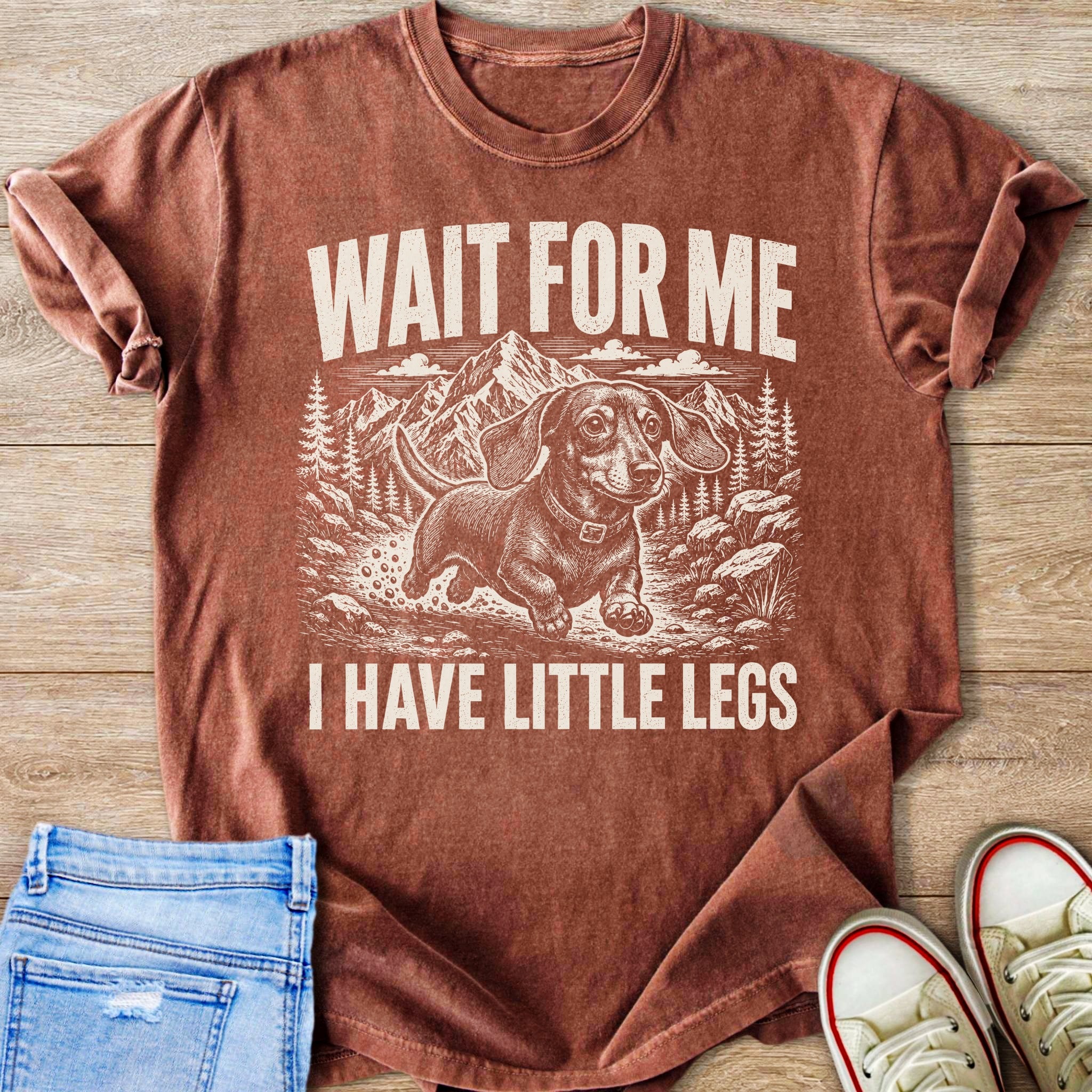 Brown t-shirt with vintage print of a dachshund running near mountains, mountains, and text "WAIT FOR ME I HAVE LITTLE LEGS".