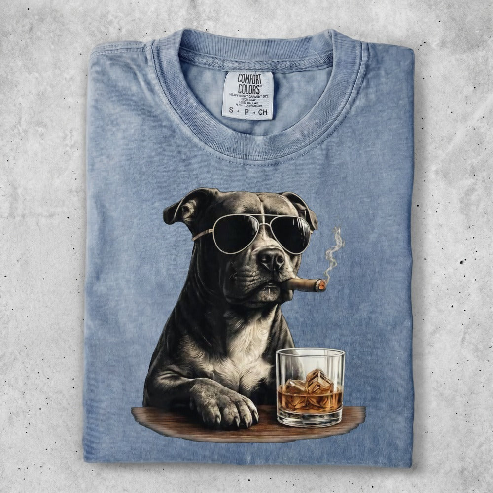 Dog wearing sunglasses and smoking cigar with whiskey.