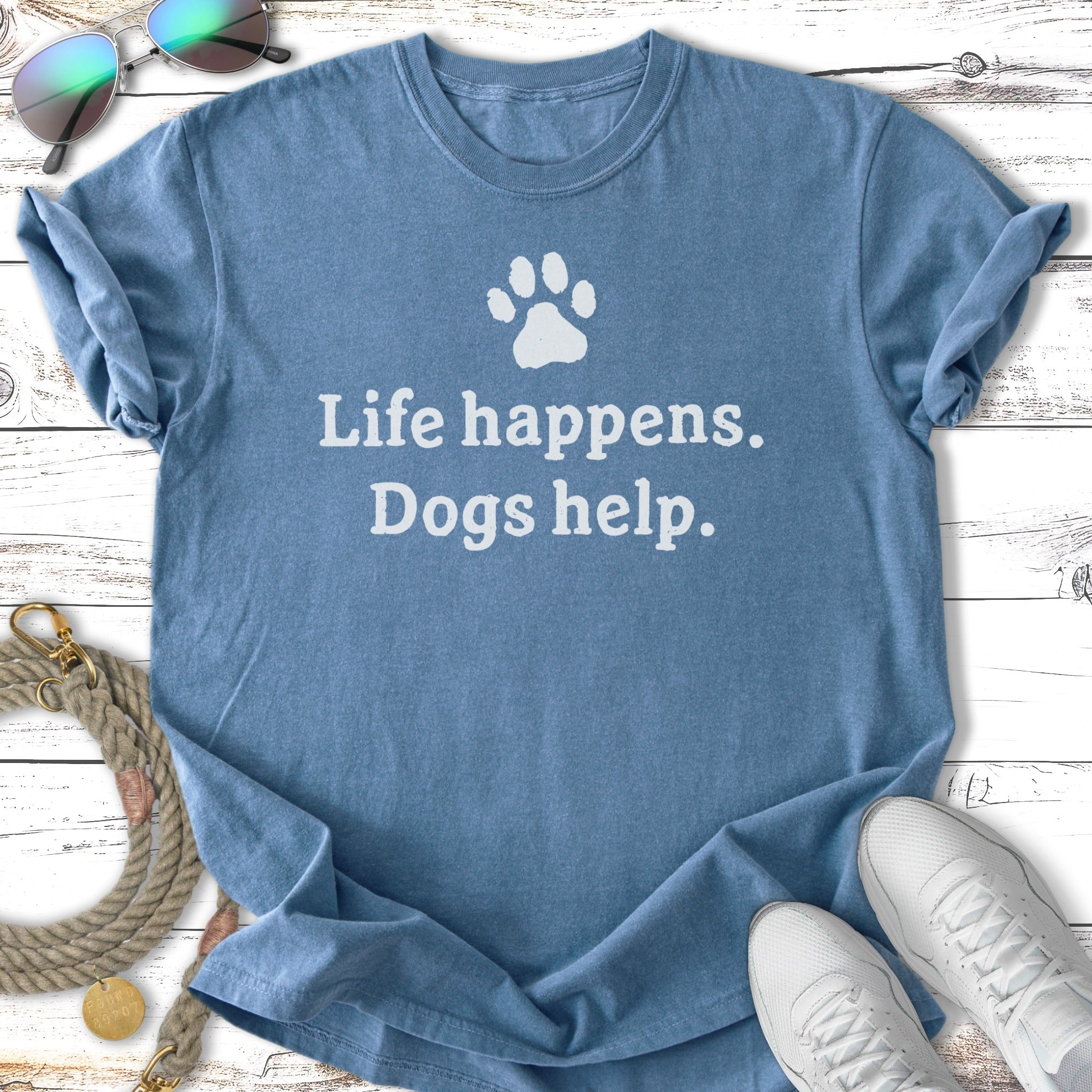 Blue t-shirt with white text "Life happens. Dogs help." and paw print.