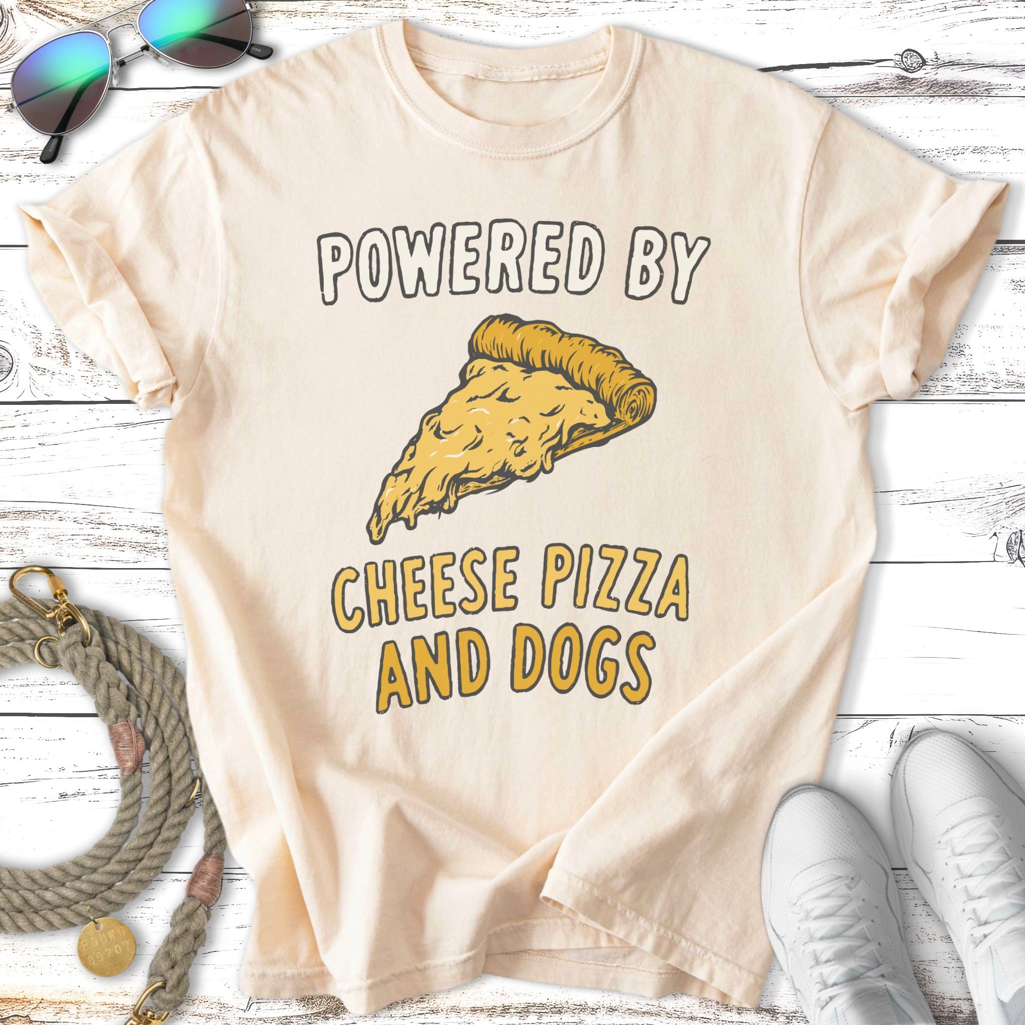 Cream t-shirt with "Powered by Cheese Pizza and Dogs" and pizza slice graphic.