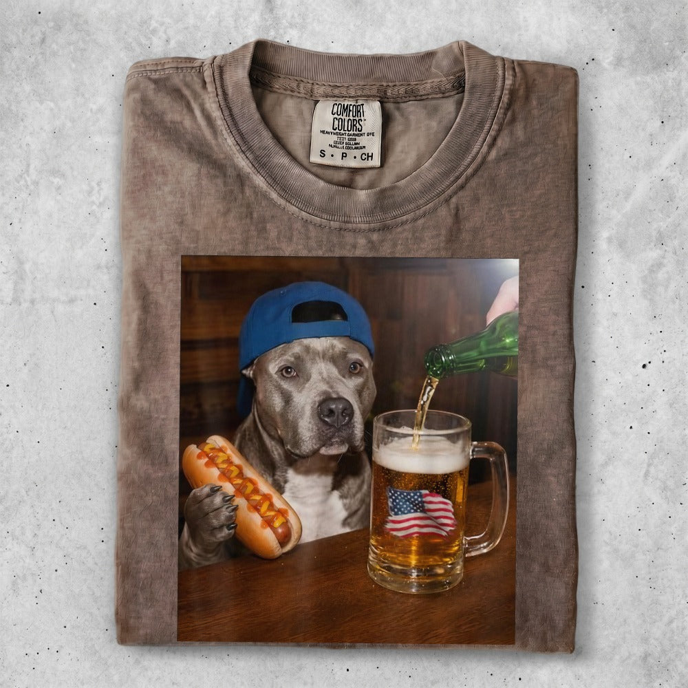 Pit bull in cap holds hot dog, mug of beer with American flag foam.