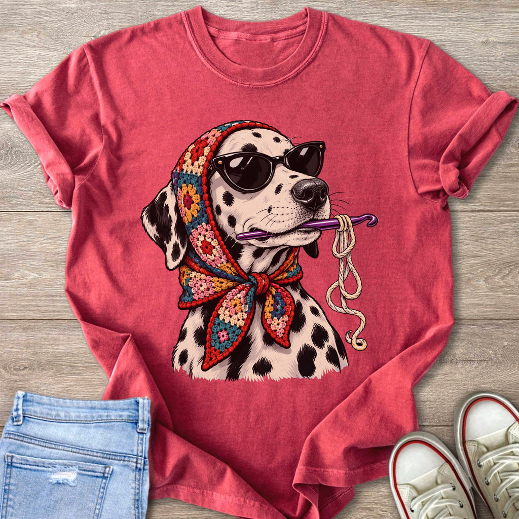 Dalmatian wearing sunglasses and a crochet scarf holds a crochet hook with yarn.