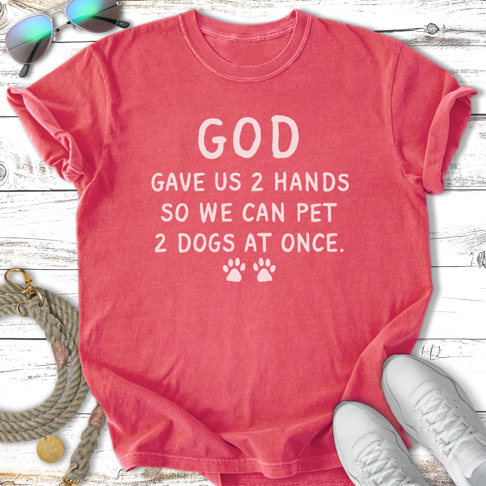 Coral t-shirt with white text reading "GOD GAVE US 2 HANDS SO WE CAN PET 2 DOGS AT ONCE."