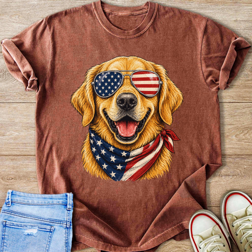 Golden retriever wearing American flag bandana and sunglasses, displayed on a brown t-shirt.