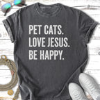 Dark gray t-shirt with "PET CATS. LOVE JESUS. BE HAPPY." text.