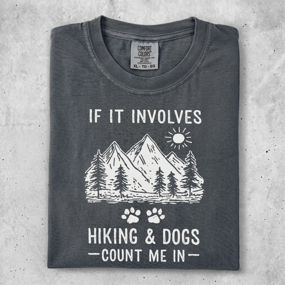 T-shirt with mountains, trees, sun, and "IF IT INVOLVES HIKING & DOGS -COUNT ME IN-" text.