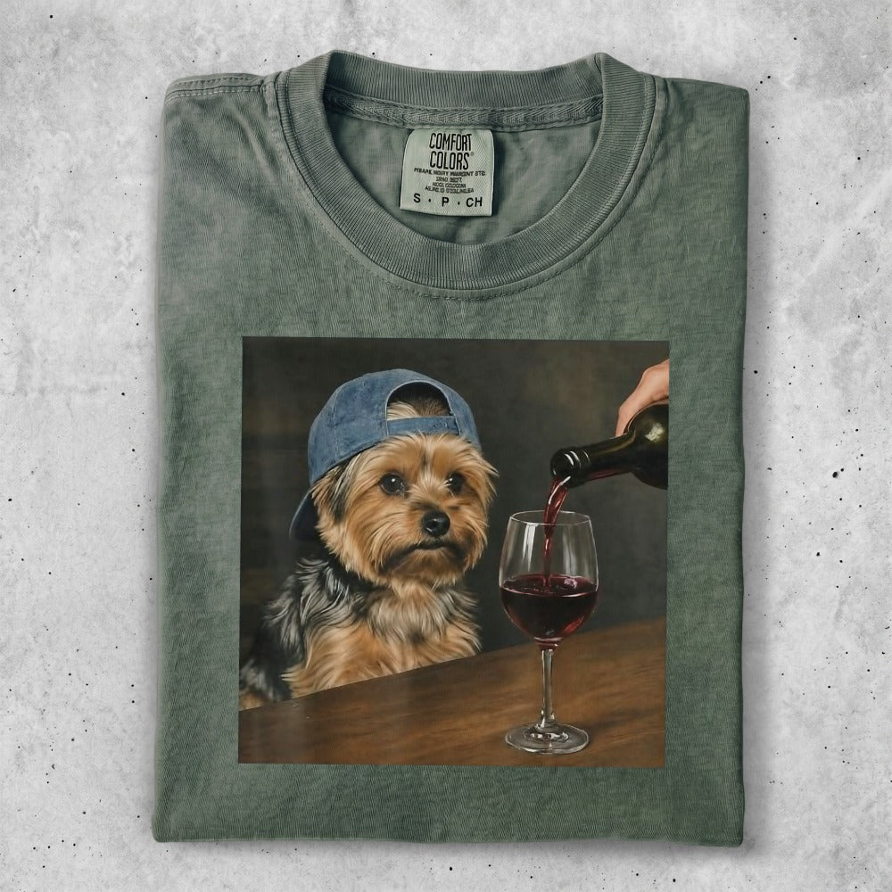 Yorkshire terrier wearing a blue baseball cap, being poured red wine.