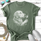 Golden retriever blowing dandelion seeds on a green t-shirt.