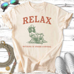 Cream t-shirt with "RELAX NOTHING IS UNDER CONTROL" and a dog in a hat.