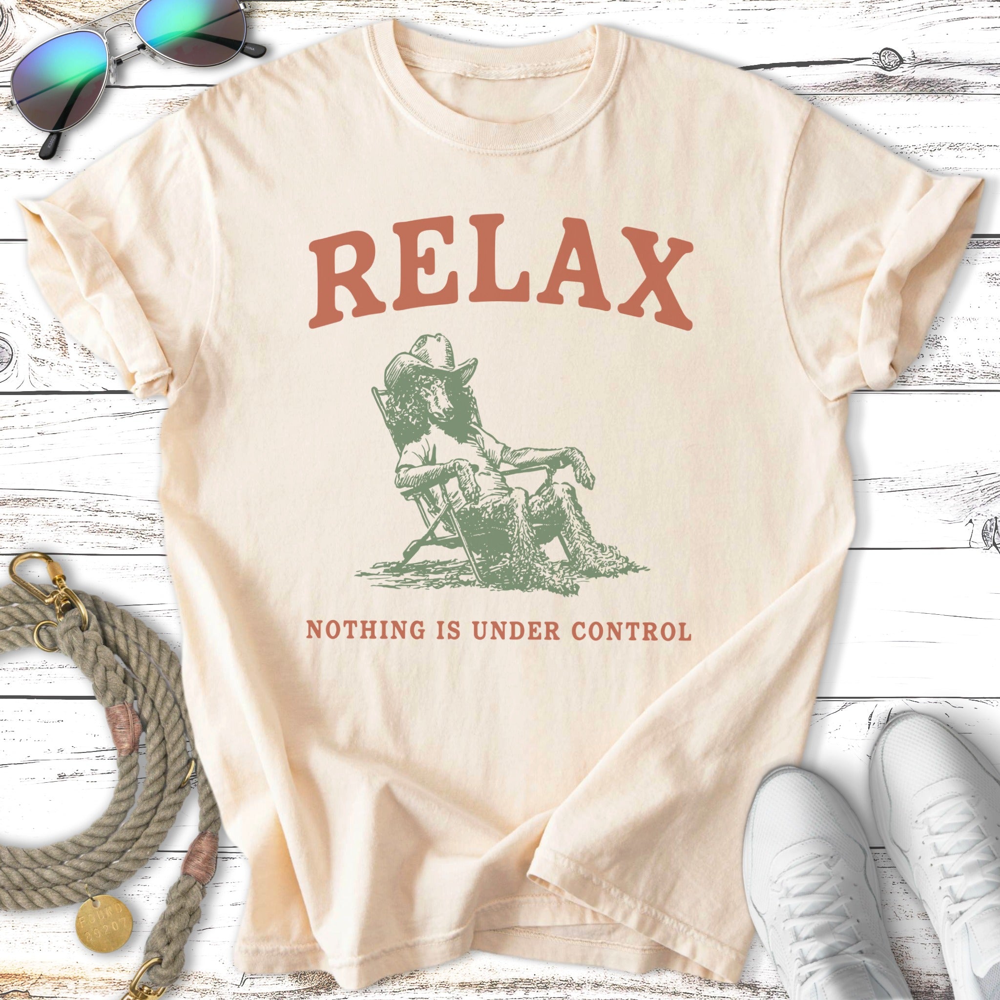 Cream t-shirt with "RELAX NOTHING IS UNDER CONTROL" and a dog in a hat.