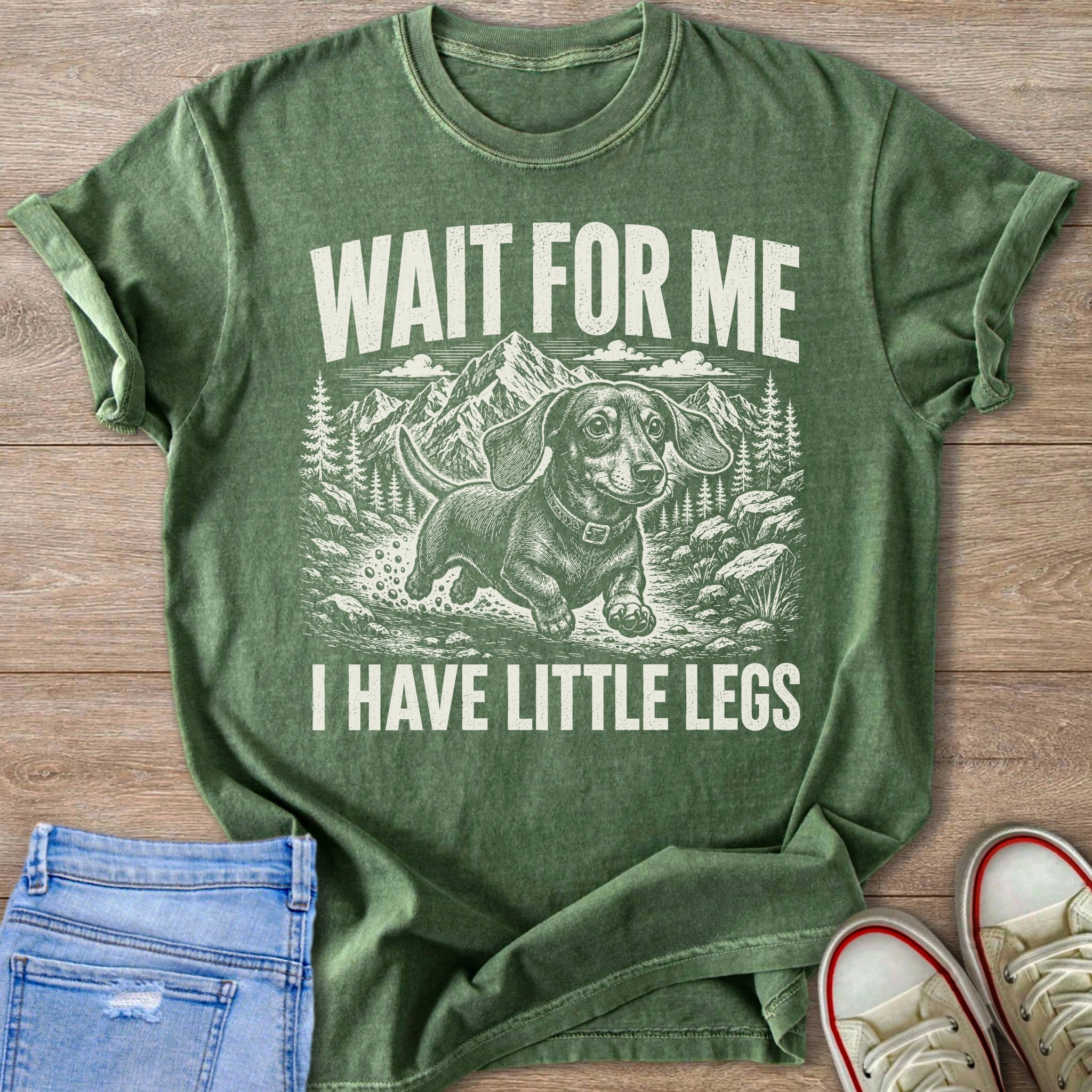 Green t-shirt with dachshund in mountains, "Wait for me I have little legs" text.